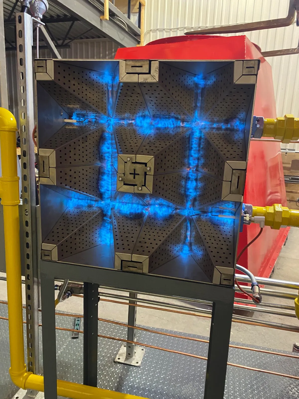 Custom process heater burner panel on test fire, blue flame across the burner face