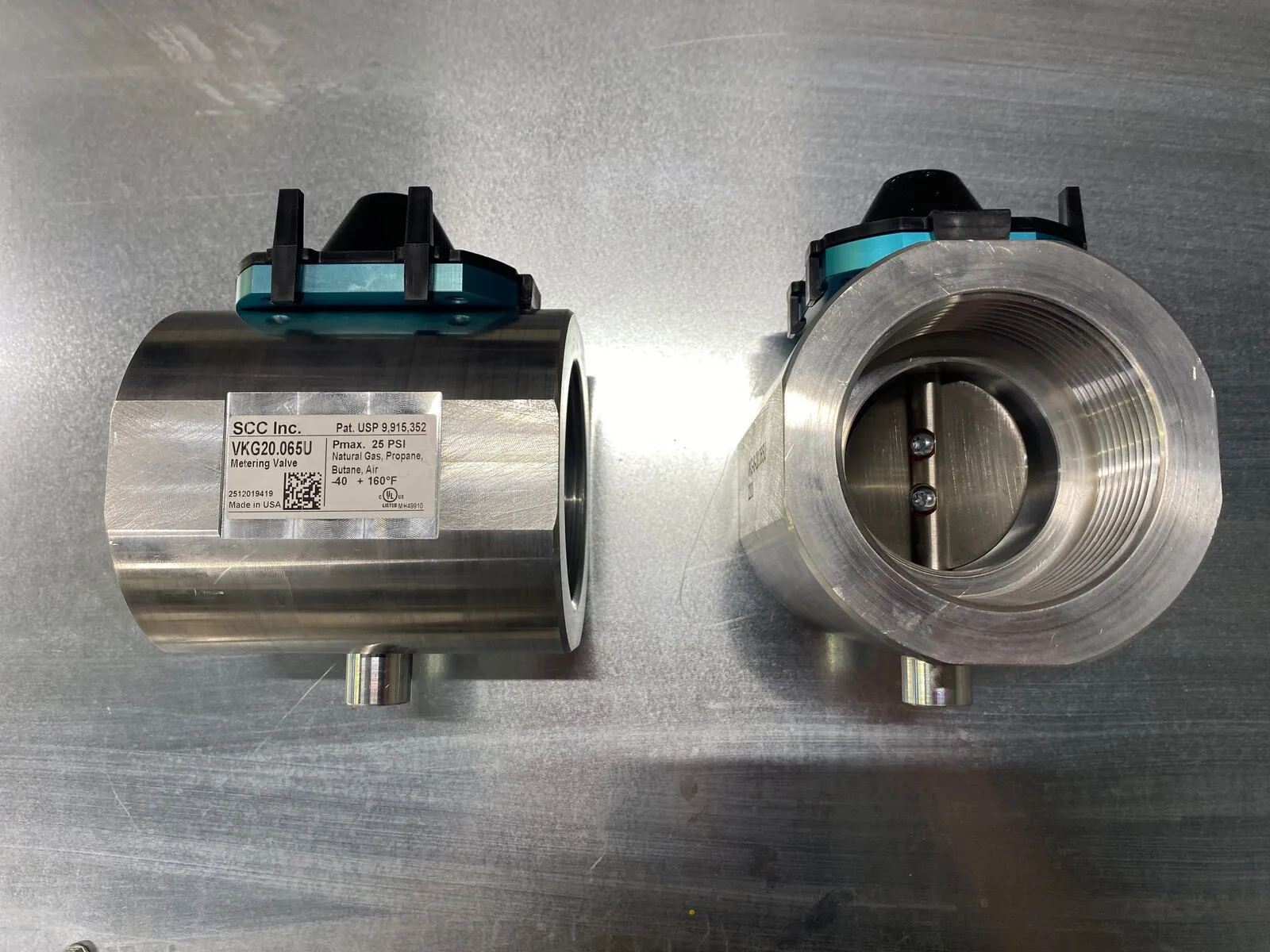 Two stainless gas metering valves on the bench, one turned to show the disc in its bore