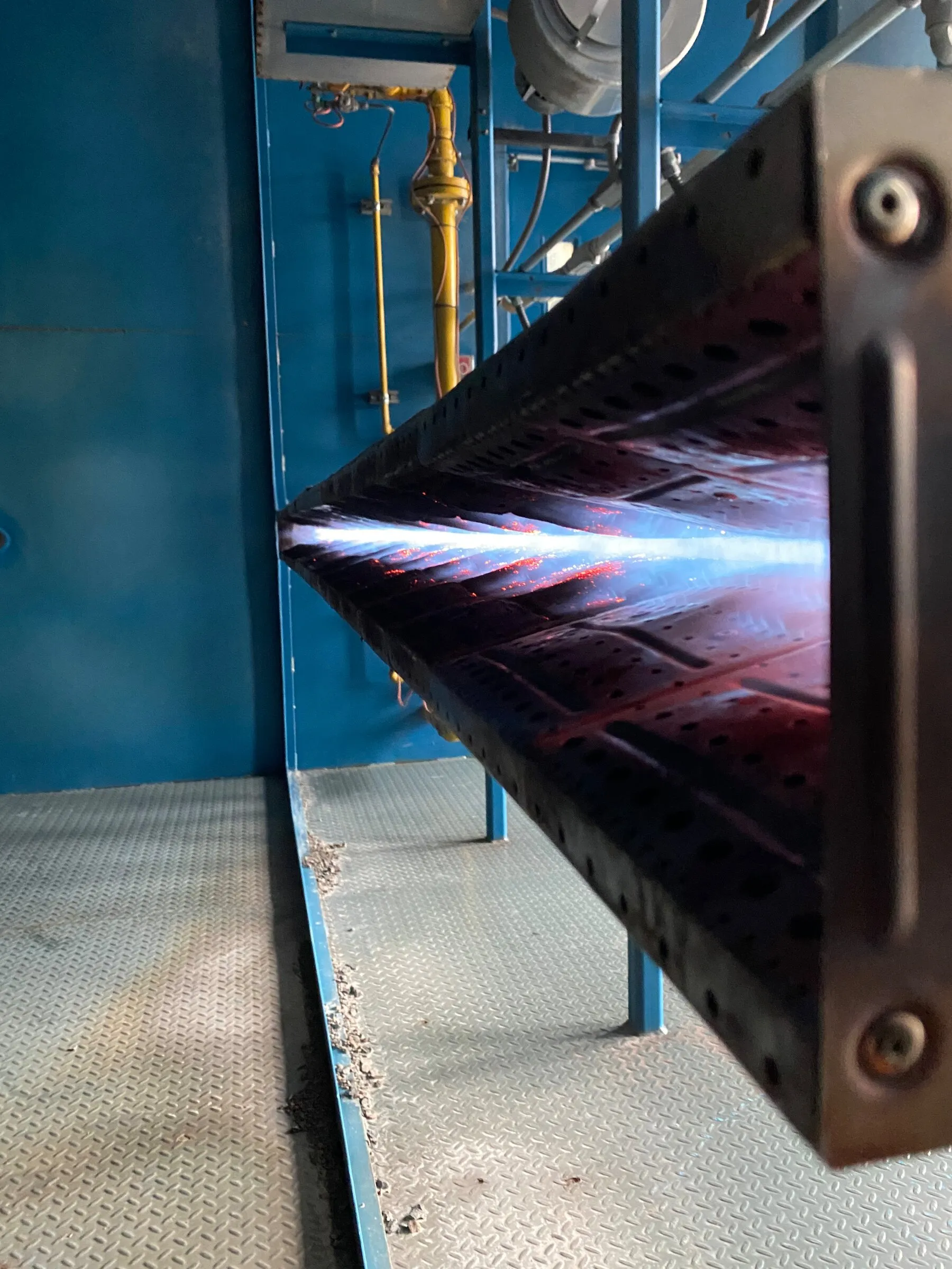 Burner manifold firing inside the blue-painted plenum of a mine air heater