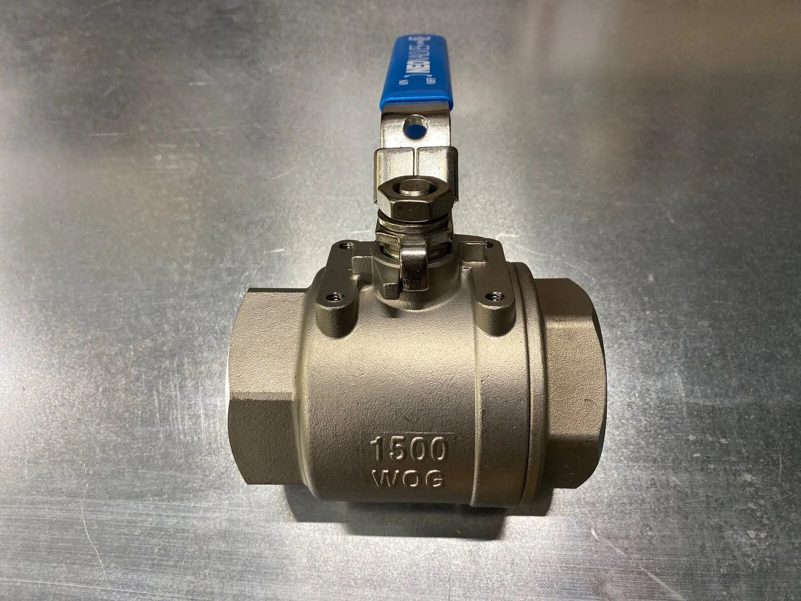 Stainless steel 1500 WOG ball valve with a blue lever handle on the bench