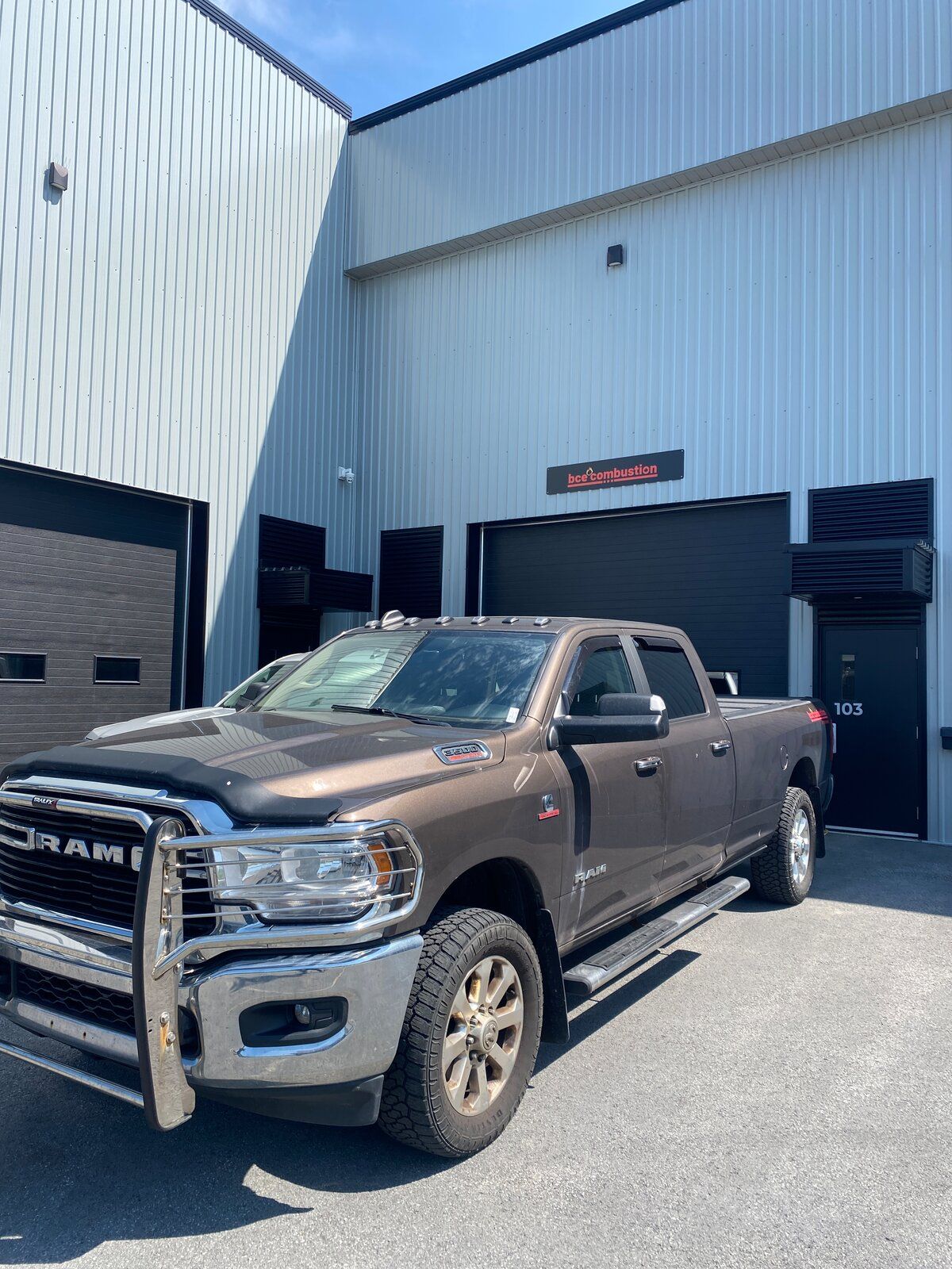 The BCE Combustion shop in Gatineau — a white steel building with the BCE Combustion sign above the bay door and a service truck parked outside